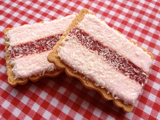 iced-vovo, galletas australianas cubiertas con tiras de foundant y mermelada de frambuesa, y espolvoreado con coco por encima